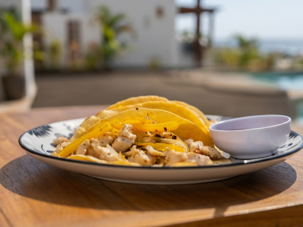 A plate of layered mango slices topped with nuts and a small dipping sauce bowl, served outdoors by a pool.