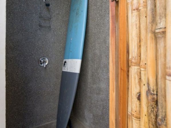 A blue-and-gray pipe runs along a concrete wall beside a wooden door, with a small valve and fixtures visible.