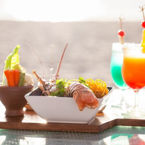 A fresh meal spread with veggie bowls, skewered items, and colorful layered drinks on a wooden tray, ready to serve.