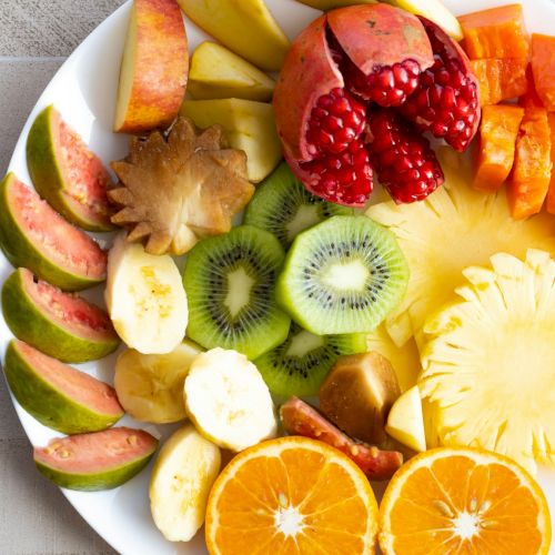 A plate of assorted sliced fruits&mdash;mango, watermelon, kiwi, pineapple, oranges, apples, and banana&mdash;ready to eat.